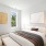 Model bedroom at our apartments for rent in Westbury, featuring wood grain floor paneling and white bedspread.